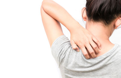 Close-up of hand touching young woman over white background