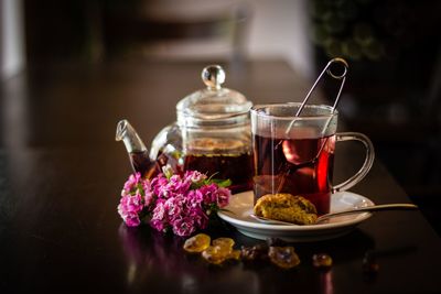 Tea glass and  tea pot decorated with cookies and flowers on wooden table in café
