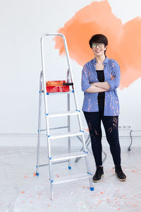 Full length portrait of young woman standing on ladder