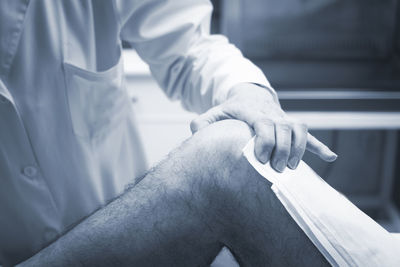 Midsection of doctor examining patient knee in hospital