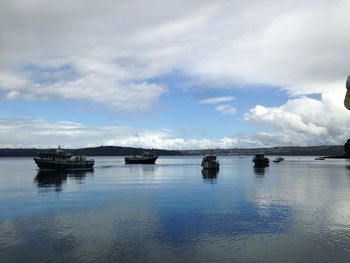 Boats in sea against cloudy sky