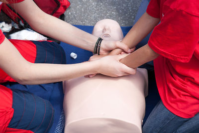 Midsection of instructor teaching paramedic while performing cpr on dummy