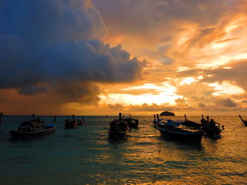 Boats in sea against sky during sunset