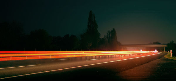 Light trails on road against sky at night