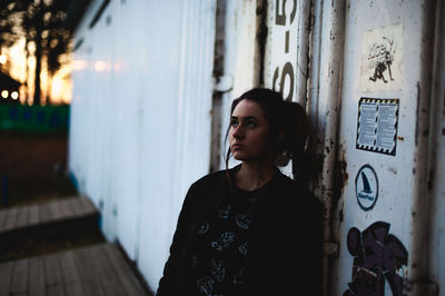 Thoughtful young woman standing by cargo container