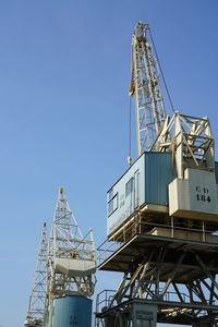 Low angle view of crane against clear blue sky