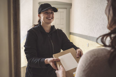 Smiling woman delivering package to customer at doorstep