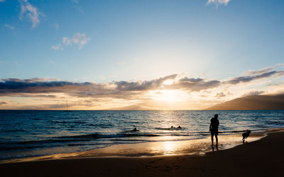 Silhouette people on beach against sky during sunset