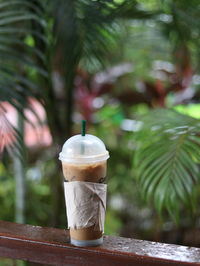 Close-up of coffee in disposable cup on railing