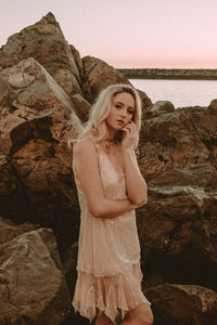 Woman standing on rock by sea against sky