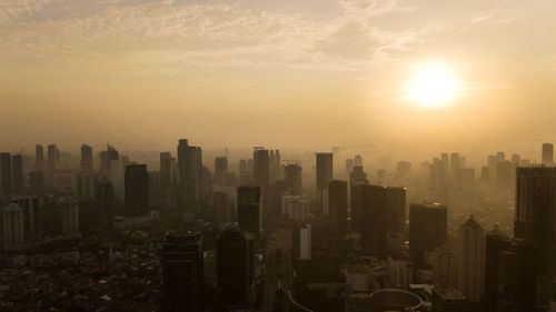 Modern buildings in city against sky during sunset