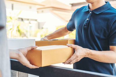 Midsection of man holding mobile phone while standing in box