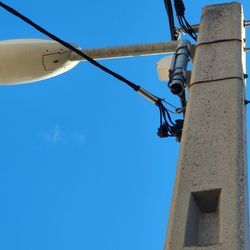 Low angle view of telephone pole against clear blue sky