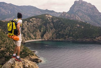 Rear view of man standing on rock by sea