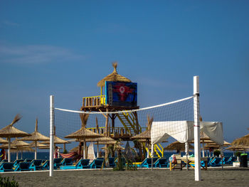 View of ferris wheel on beach against blue sky