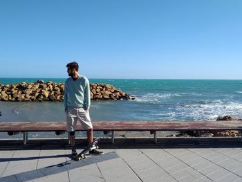 Man standing at sea shore against clear sky