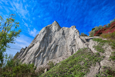 Low angle view of rocky mountains against blue sky