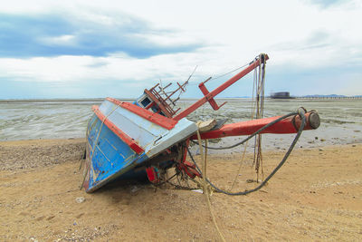 Abandoned ship moored on beach against sky