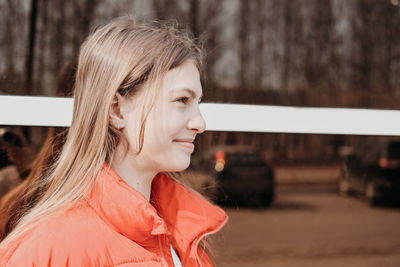 Happy smiling teenager girl in winter jacket standing against window wall. street portrait 