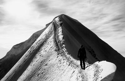 Rear view of hiker on mountain against sky