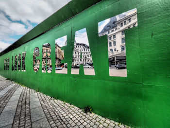 Information sign on grass in city against sky