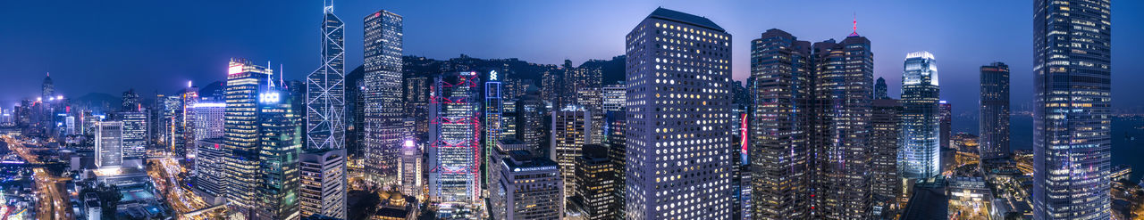 Illuminated modern high rises in hong kong financial district against sky at blur hour