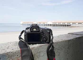 Close-up of camera on beach against sky