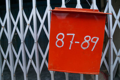 Close-up of red signboard against fence