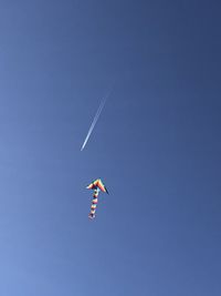 Low angle view of airplane flying against clear blue sky