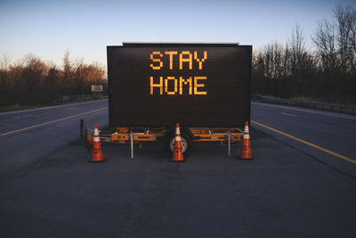 Road sign on street against sky