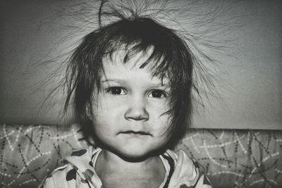 Close-up portrait of cute girl with tousled hair against wall