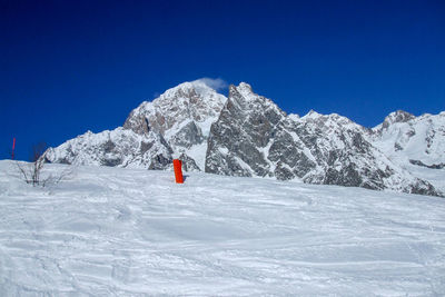 Person on snowcapped mountain against clear blue sky