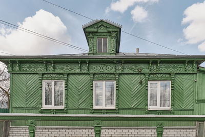 Facade of typical russian rural house with dormer window on roof and carved wooden decorations