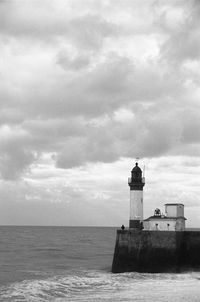 Lighthouse by sea against sky