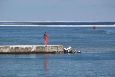 Lighthouse by sea against sky