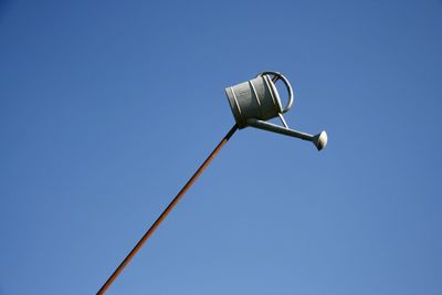 Low angle view of watering can on pole against clear blue sky