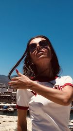 Low angle view of woman against clear blue sky