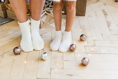 Low section of people standing on tiled floor by christmas decoration