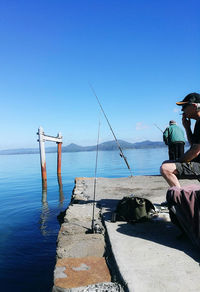 Man smoking cigarette by river against sky