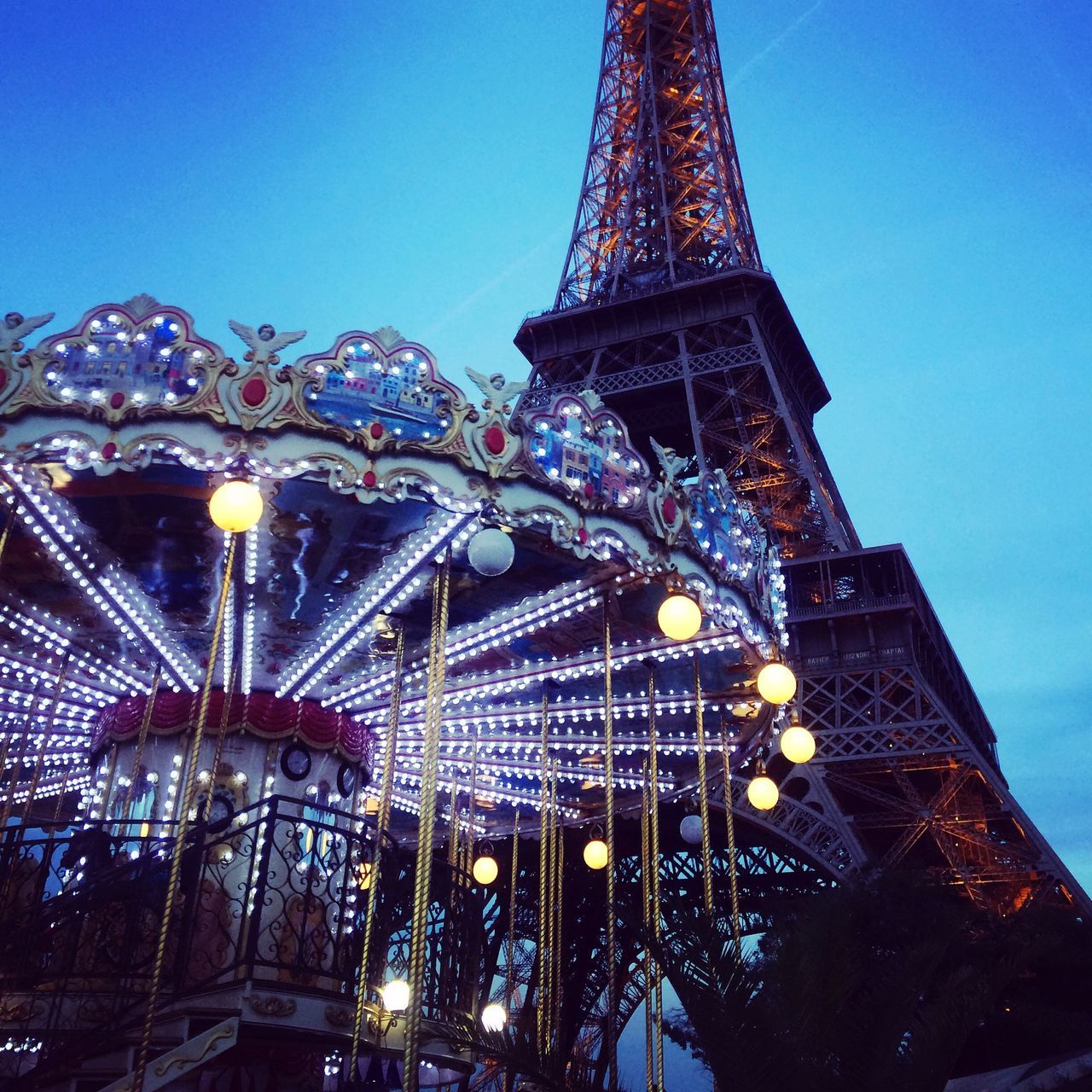 architecture, built structure, famous place, low angle view, travel destinations, blue, international landmark, clear sky, illuminated, tower, tourism, capital cities, tall - high, eiffel tower, travel, building exterior, city, metal, sky, night