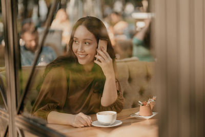 Portrait of smiling young woman using smart phone in cafe