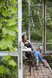 Female gardener resting in glass house