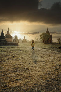 People in temple building against sky during sunset