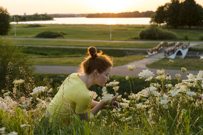 Woman with eyes closed smelling white wildflower