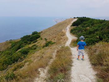 Rear view of man on shore against sky