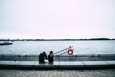 Men sitting on boat in lake against sky