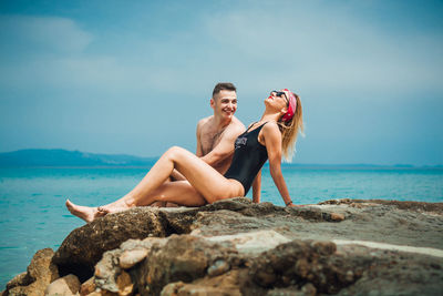 Young couple spending leisure time at beach against sky