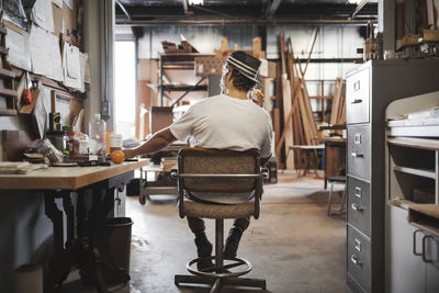 Rear view of carpenter sitting on chair at workshop