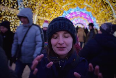 Woman with eyes closed against illuminated decoration during christmas