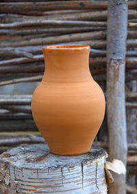 Clay jug on a stump and a wooden fence